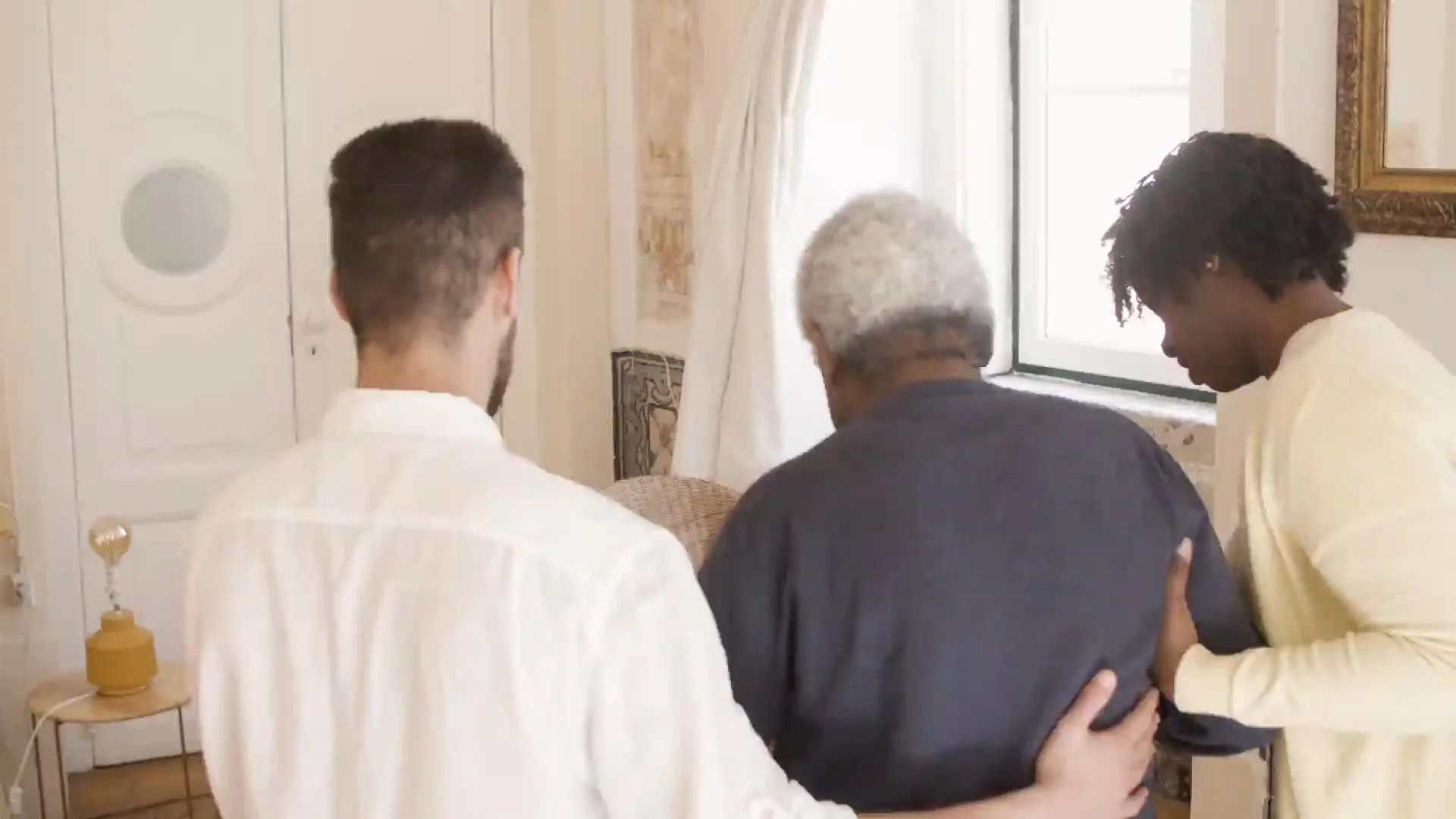 Two caregivers helping elderly man walk
